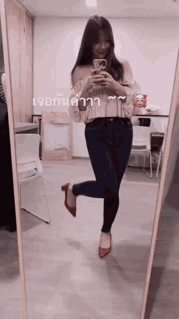 a woman taking a picture of herself in front of a mirror with chinese writing