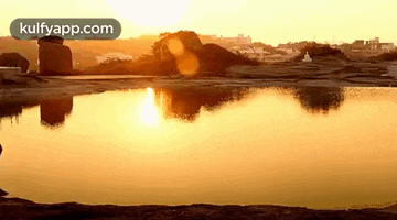 a sunset over a lake with a reflection of the sun in the water .