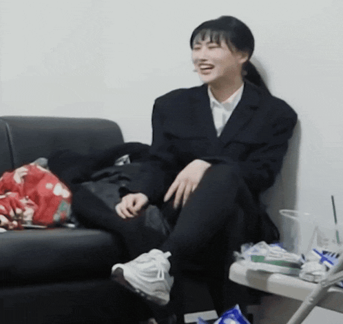 a woman in a suit sits on a couch with her legs crossed