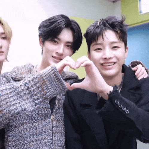 two young men are making a heart shape with their fingers