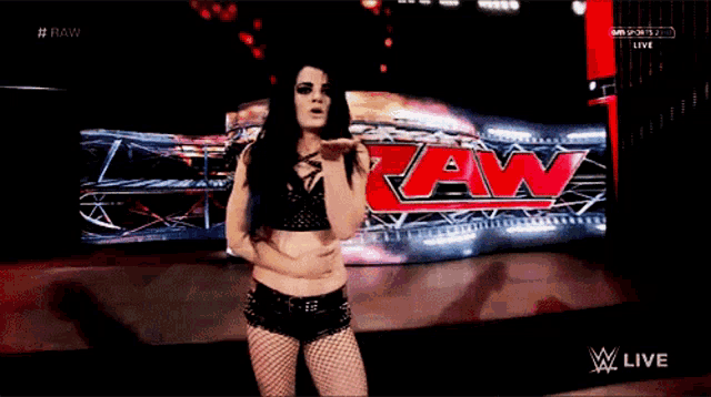 a female wrestler stands in front of a sign that says raw