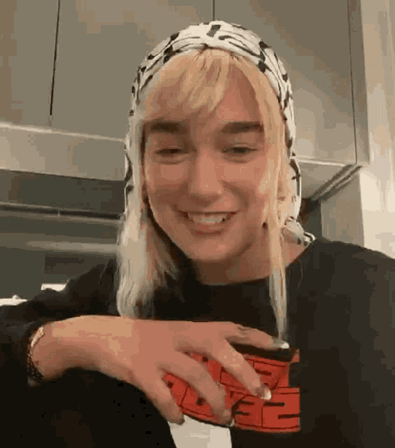 a woman wearing a head scarf and a black shirt is smiling and looking at the camera .