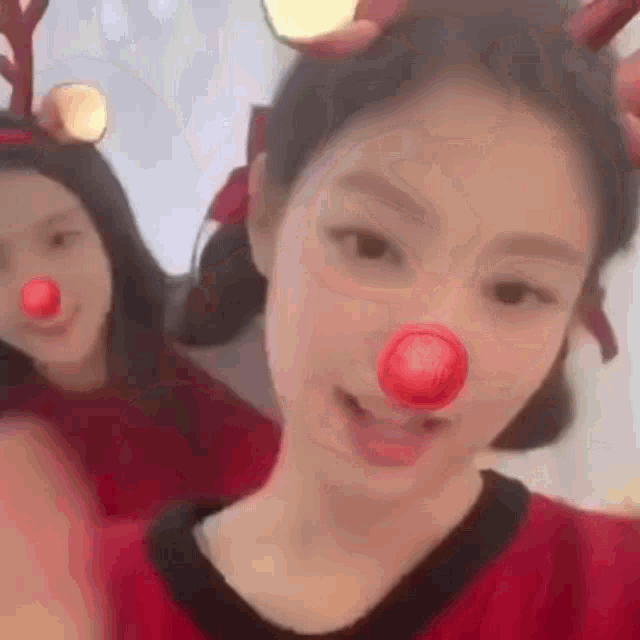 a girl wearing a reindeer headband and a red nose .