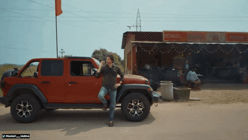 a red jeep is parked in front of a building that says ' prakash warna ' on it