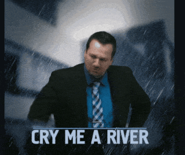 a man in a suit and tie is standing in the rain with the words cry me a river below him