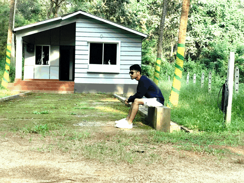 a man sits in front of a small house