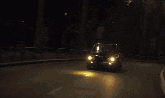 a car is driving down a street at night with the lights on