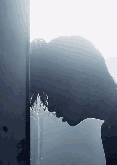 a silhouette of a person leaning against a wall with their head down