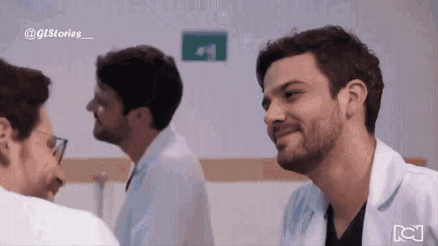 a man in a lab coat is smiling in front of another man