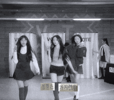a black and white photo of three girls dancing in front of a sign that says vote