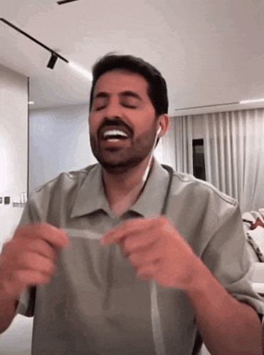 a man with a beard is wearing ear buds and making a funny face
