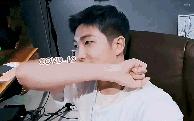 a man covering his mouth with his hand with the word covid-19 written on his arm