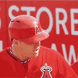 a baseball player is standing in front of a store sign