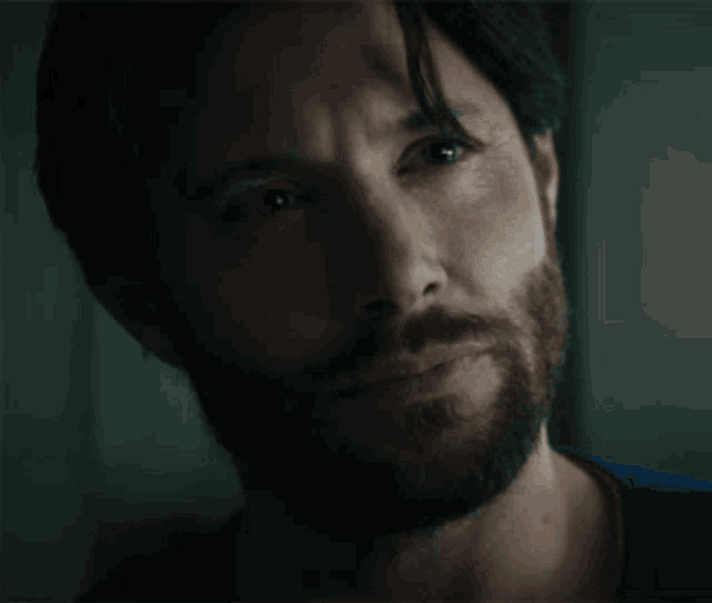 a close up of a man 's face with his eyes closed and a beard