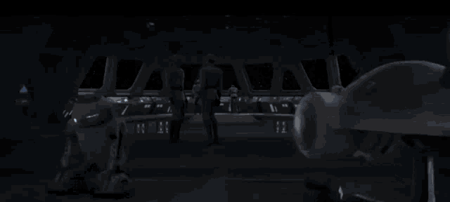 a group of people standing in a dark room with a umbrella in the foreground