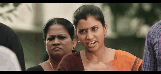 a woman is making a funny face while standing next to another woman in a crowd .