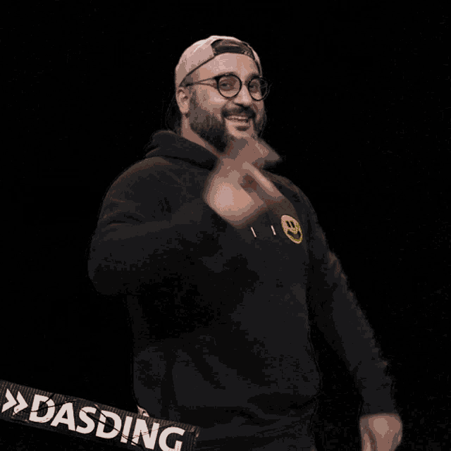 a man wearing a black hoodie with a yellow smiley face on the front