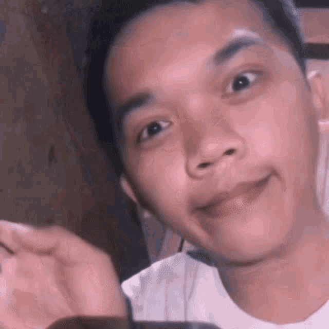 a young man in a white shirt is smiling and looking at the camera