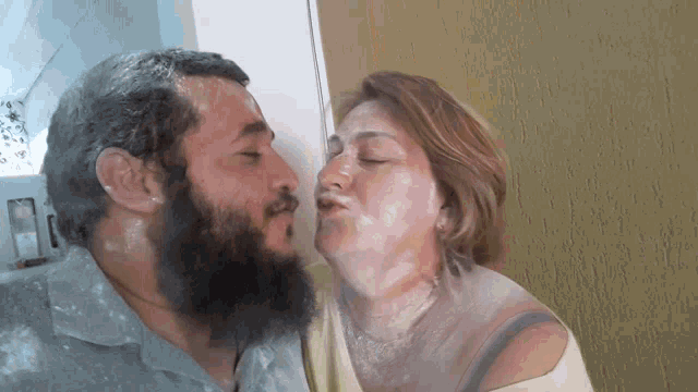 a man with a beard kisses a woman on the cheek covered in flour