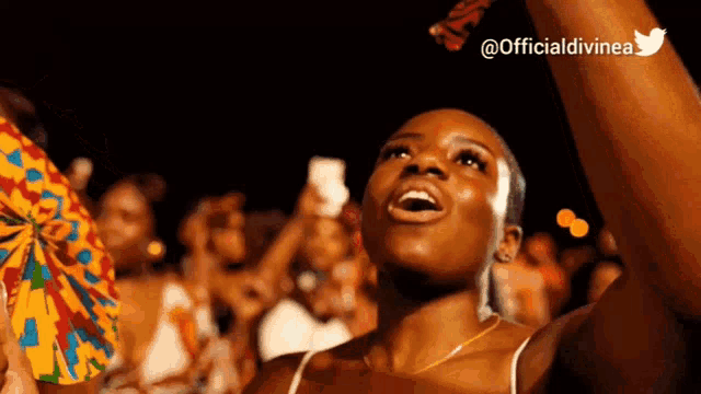 a woman in a crowd with her arms in the air and a twitter logo