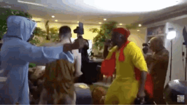 a group of people are dancing together in a living room . one of the people is wearing a yellow shirt .