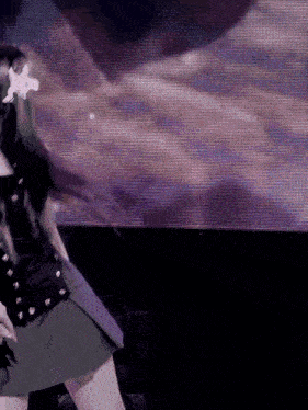 a woman in a skirt is dancing in front of a screen