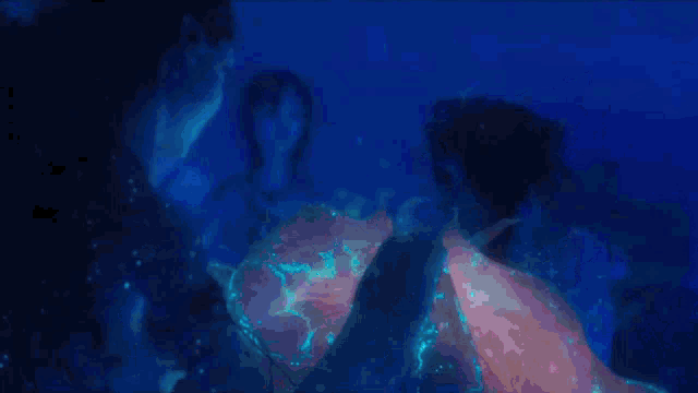 a group of people are swimming in the water with a glowing object in the background .