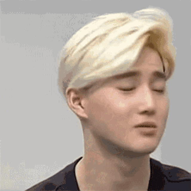 a close up of a young man with blonde hair making a funny face .