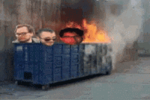 a group of people are sitting in a dumpster with flames coming out of it