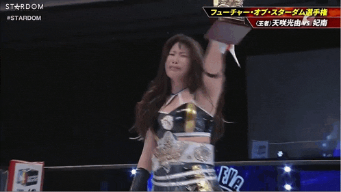 a woman in a wrestling ring holding a trophy with the word stardom on the bottom right