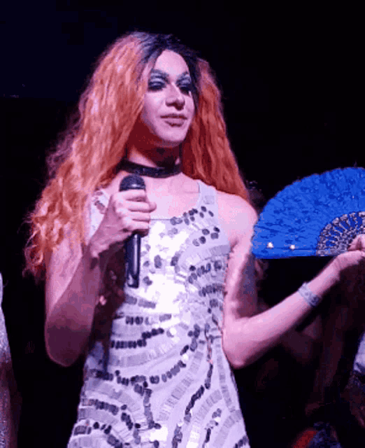 a woman in a sequined dress is holding a fan and a microphone