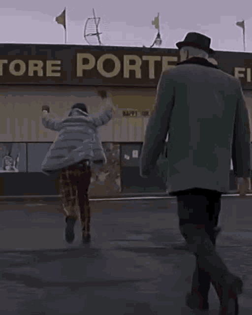 a man in a green coat walking in front of a store called store port