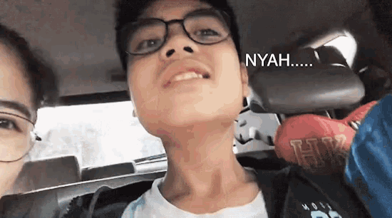 a boy with glasses is sitting in the back seat of a car with the word nyah written on the back