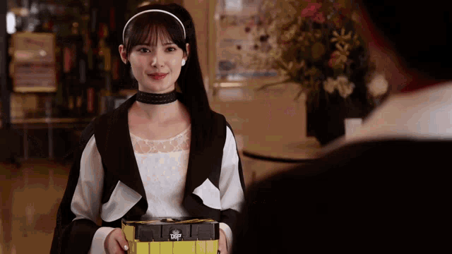 a woman in a black and white outfit is holding a box that says ' tdf ' on it