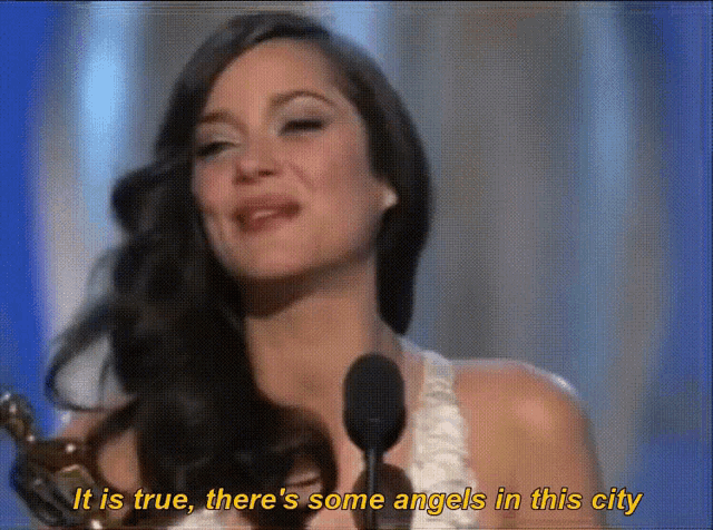 a woman speaking into a microphone with the words " it is true there 's some angels in this city "