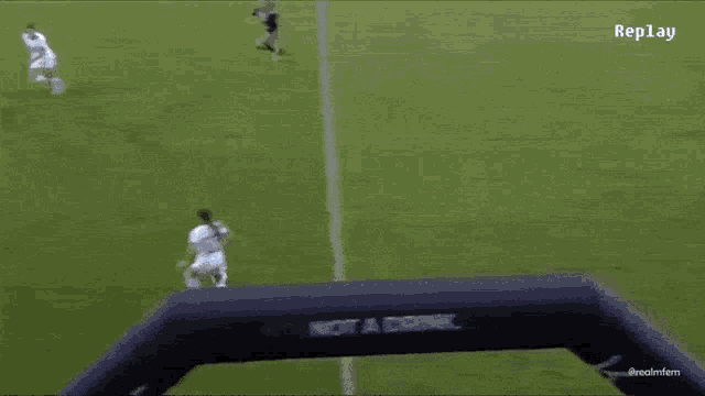 a soccer game is being played on a field with replay in the corner