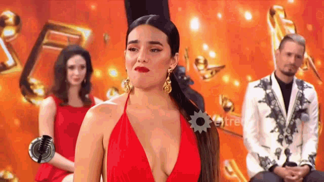 a woman in a red dress is standing in front of a group of people .