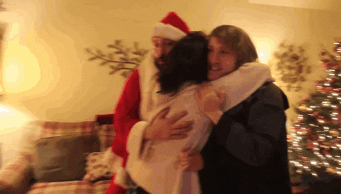 a man in a santa hat is hugging a woman