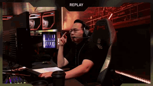 a man wearing headphones sits in front of a screen that says replay on it