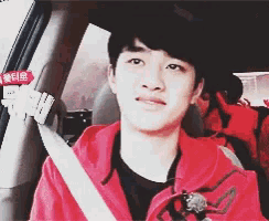 a young man in a red jacket is sitting in a car with a sign that says ' eee ' on it
