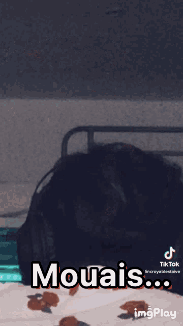 a person laying on a bed with the words mouais written on the screen