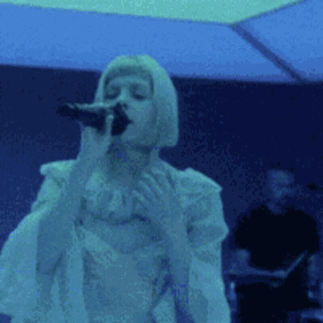 a woman singing into a microphone with a man in the background
