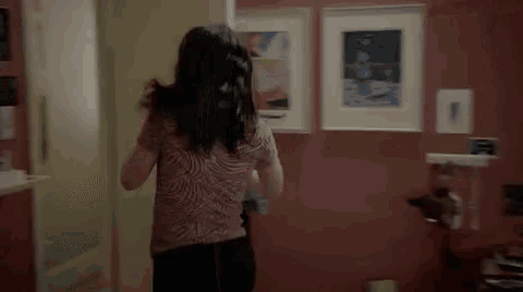 a woman is standing in a room with a red wall and a painting on the wall .