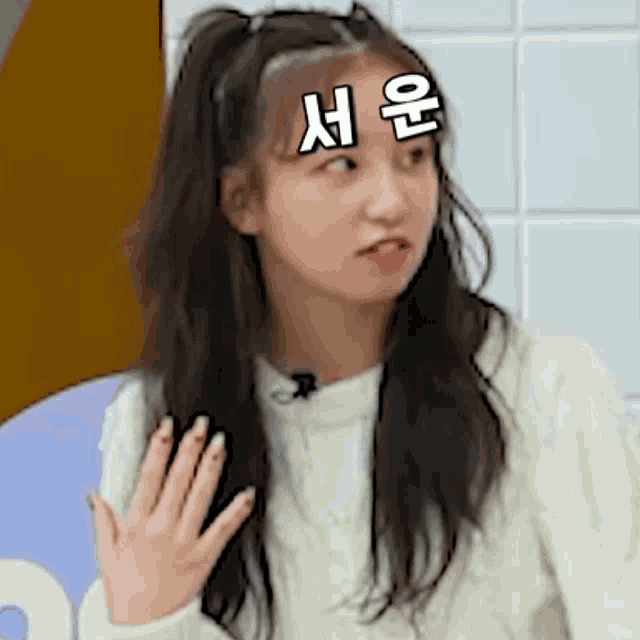 a young girl with a ponytail is making a funny face with her hand .