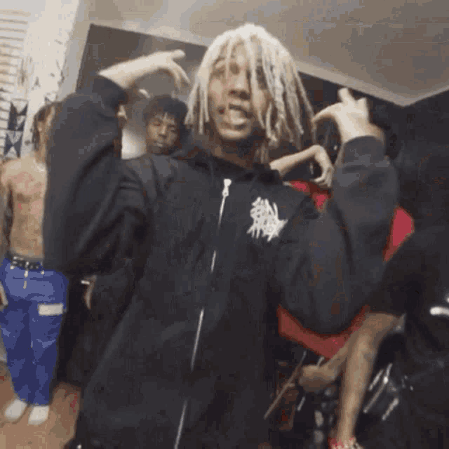 a man with dreadlocks is making a funny face in a room full of people