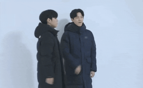 a group of young men are standing next to each other wearing jackets .