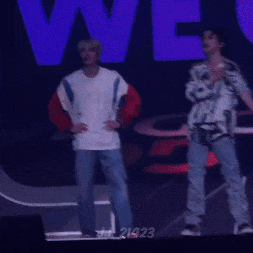 a man in a white shirt is dancing on a stage in front of a sign that says " we "