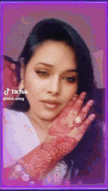 a tiktok video of a woman with a red henna design on her hand