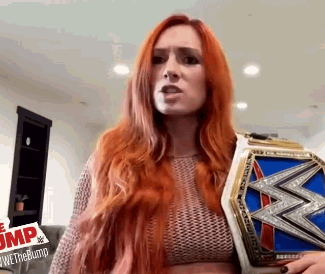 a woman with red hair is holding a wrestling championship belt