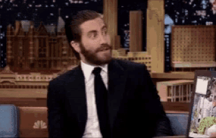 a man with a beard wearing a suit and tie is sitting at a table